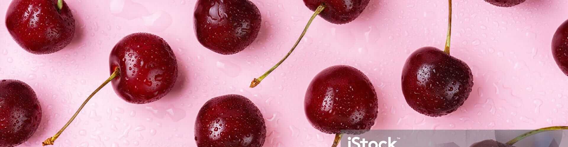 Fresh red cherries with water droplets scattered on a pink background