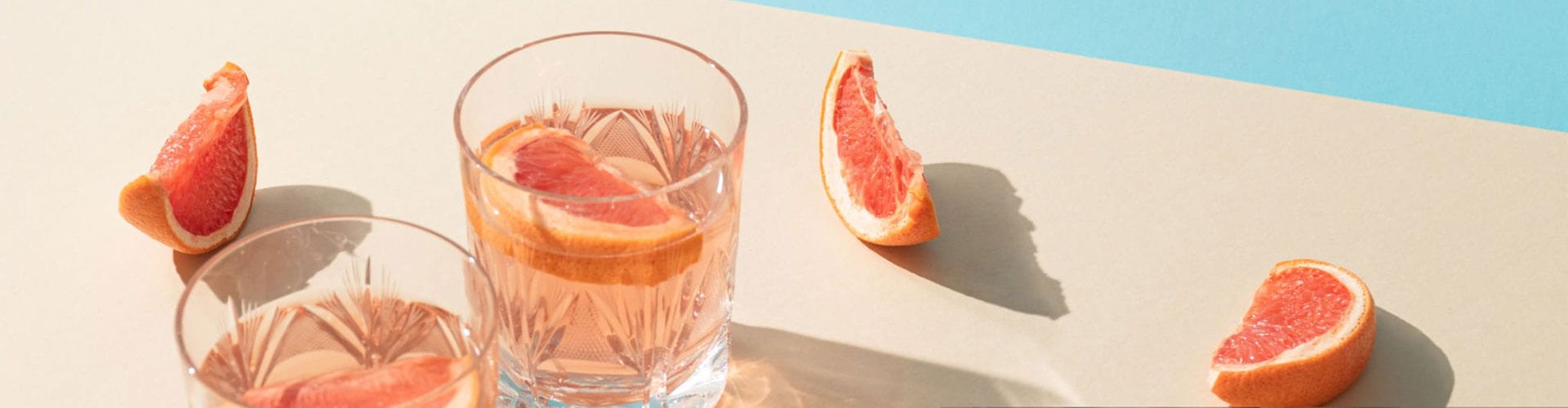 Pink grapefruit drinks in glasses with fresh grapefruit slices.